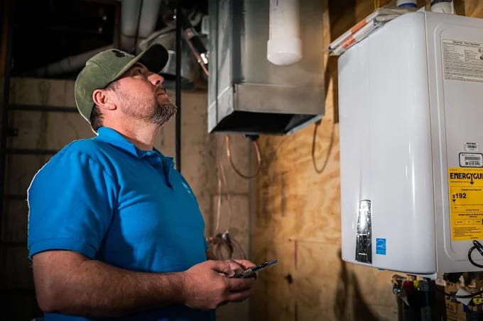 A professional plumber inspecting a tankless unit to determine the cause of a water heater leaking from bottom.