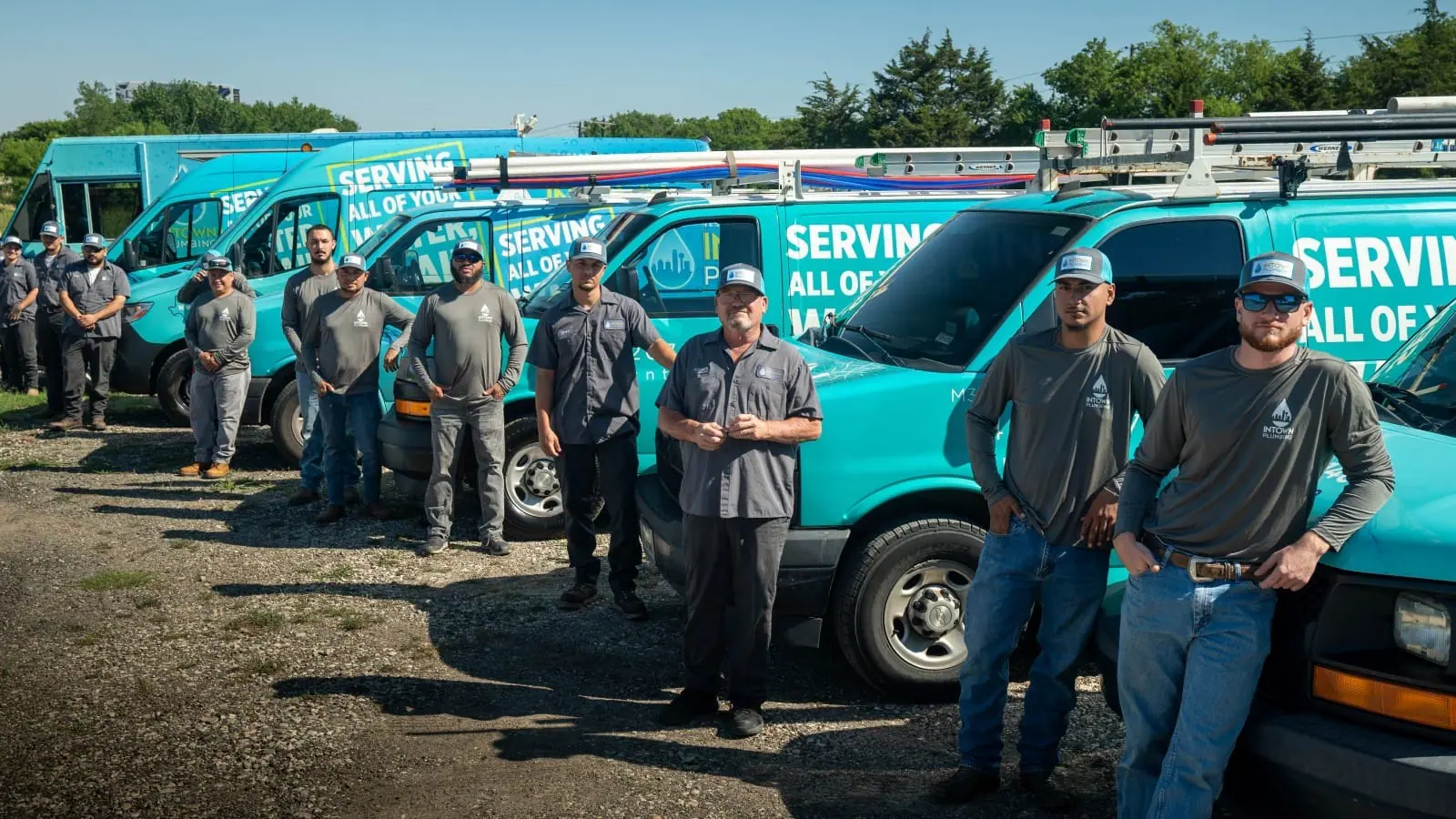Intown Plumbing service team standing in front of their teal service vans in Dallas-Fort Worth area