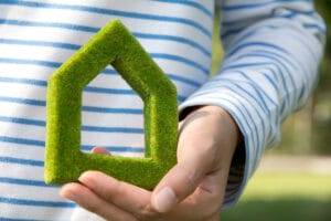 Person holding a green, house-shaped symbol, representing eco-friendly gas consumption and sustainable living.