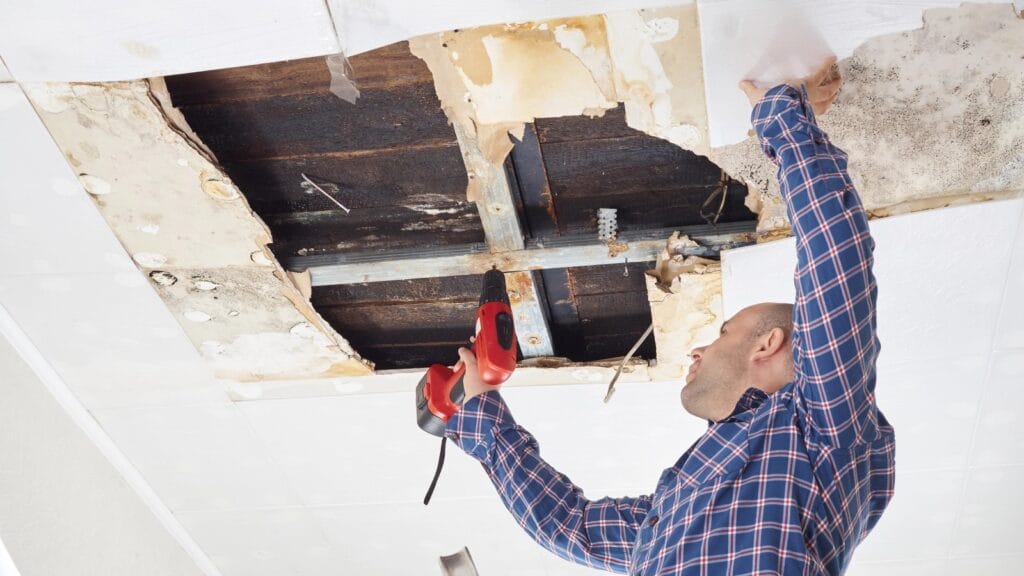  Man repairing a severely damaged ceiling caused by water leak