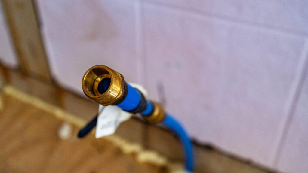 Close-up of a dishwasher drain hose fitting, highlighting plumbing connections involved in fixing and preventing clogs.