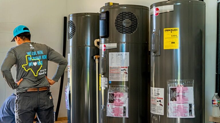 A plumber inspecting multiple high-efficiency Rheem water heaters, emphasizing professional installation and maintenance for optimal energy savings.