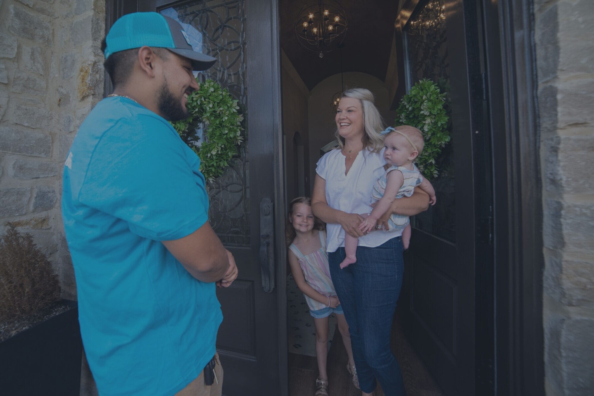 Friendly Intown Plumbing technician greeting a happy mom and her children at their home in Rockwall, TX