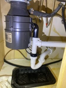 Under-sink view of a garbage disposal and P-trap after repair in Rowlett, TX