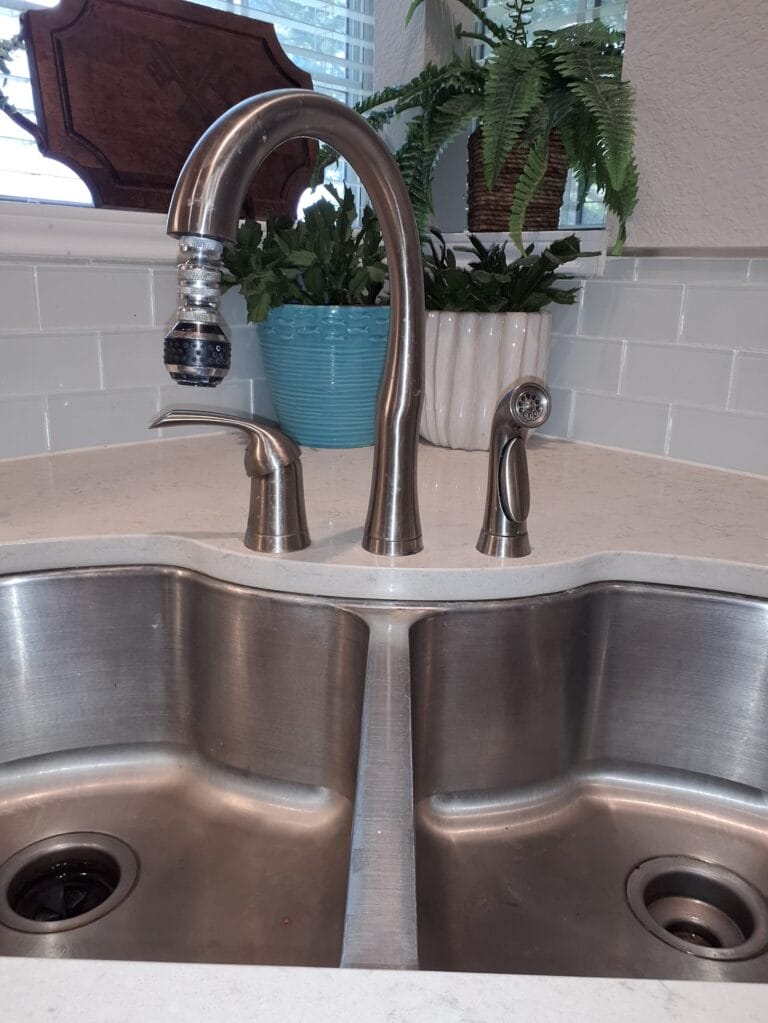 Kitchen faucet sprayer with hard-water mineral buildup on the nozzle, the kind of scaling North Texas water causes