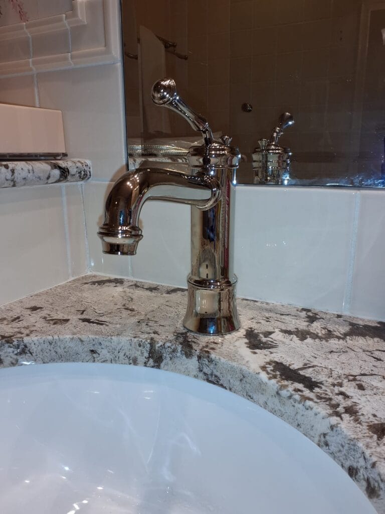 A polished chrome bathroom faucet installed on a granite countertop, representing professional plumbing repair services by Intown Plumbing.