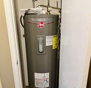 A grey Rheem Performance Plus water heater installed in a closet as part of a warranty repair service by Intown Plumbing.