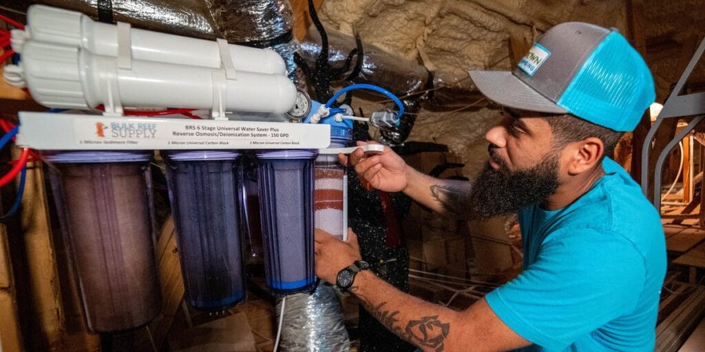 An Intown Plumbing technician installs a Bulk Reef Supply reverse osmosis water filtration system in an attic space.